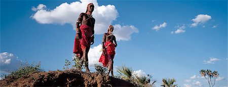 Deux guerriers Samburu resplendissantes avec Ochred longue tresses et ornements perlés relax dans une pose typique à côté d'une berge de la rivière. Photographie de stock - Rights-Managed, Code: 862-03366316