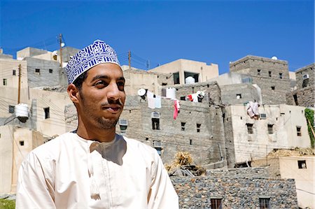 Oman,Western Hajar Mountains,Wadi Bani. A remote mountain village of Balad Seet,a local man looks outwards with his traditional home behind him. Foto de stock - Con derechos protegidos, Código: 862-03360312