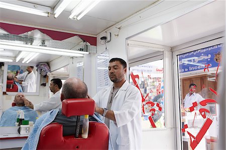 Oman,Dhofar. A visitor to Salalah has a close shave in a typical barber’s shop. Stock Photo - Rights-Managed, Code: 862-03360343