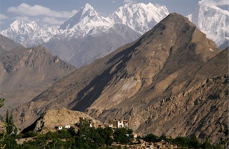 pakistan - The jagged peaks and bare hills of the Karakorum Range dominate the skyline of Karimabad. The Baltit Fort towers over the village. Stock Photo - Rights-Managed, Code: 862-03360394