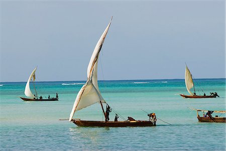 ship sailing - East Africa; Tanzania; Zanzibar. A dhow is a traditional Arab sailing vessel with one or more lateen sails. It is primarily used along the coasts of the Arabian Peninsula,India,and East Africa. Stock Photo - Rights-Managed, Code: 862-03437407