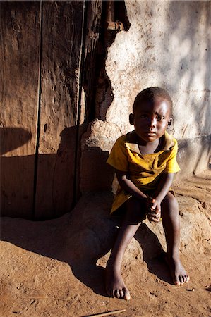 sad african children - Malawi, Lilongwe, Ntchisi Forest Reserve. An small boy sits by the entrance to his house in a mountain village. Stock Photo - Rights-Managed, Code: 862-03713090