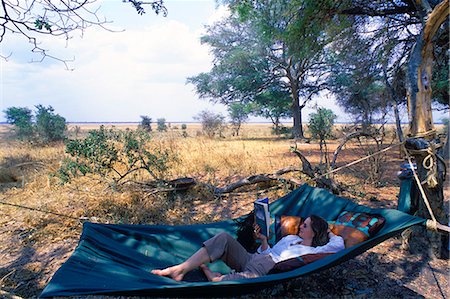 Tanzania, Katavi National Park. Relaxing reading a book in a hammock at Chada Camp. Stock Photo - Rights-Managed, Code: 862-03713917