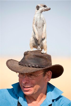 suricata suricatta - Botswana, Makgadikgadi. A man with a meerkat hat. Stock Photo - Rights-Managed, Code: 862-03736351