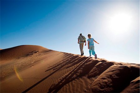 simsearch:862-03365353,k - Sossusvlei, Namib-Naukluft National Park, Namibia. A young girl and a safari guide scale a sand dune in the Namib Desert. Stock Photo - Rights-Managed, Code: 862-03737009