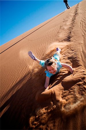 simsearch:862-03365353,k - Sossusvlei, Namib-Naukluft National Park, Namibia. A young girl slides and tumbles down a sand dune in the Namib Desert. Stock Photo - Rights-Managed, Code: 862-03737010