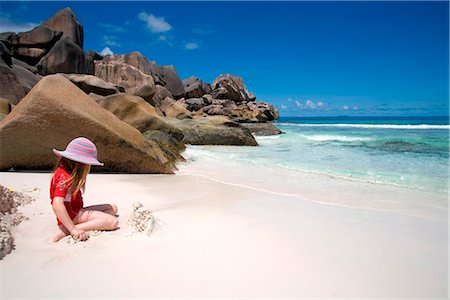 Seychelles, La Digue, Grande Anse. Girl playing on a stunning coral-sand beach with boulders in the background. Stock Photo - Rights-Managed, Code: 862-03737085