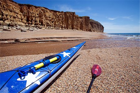 England, Dorset, Bridport.  A sea kayak rests in the shadow of the famous cliffs of the UNESCO World Heritage Jurassic Coast. Stock Photo - Rights-Managed, Code: 862-03807386