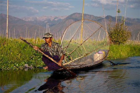 Myanmar, Inle Lake.  Intha fisherman with traditional conical fish net, gently paddling his flat-bottomed boat home. Stock Photo - Rights-Managed, Code: 862-03807938