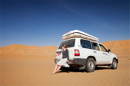 dune driving - Oman, Empty Quarter. A young lady takes a break from driving to enjoy the views. Stock Photo - Rights-Managed, Code: 862-03808176