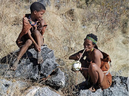 simsearch:862-03820241,k - A NIIS boy watches a woman quench her thirst by sucking water through a hollow reed from a blown ostrich egg. They live in the harsh environment of a vast expanse of flat sand and bush scrub country straddling the Namibia Botswana border. Stock Photo - Rights-Managed, Code: 862-03820233