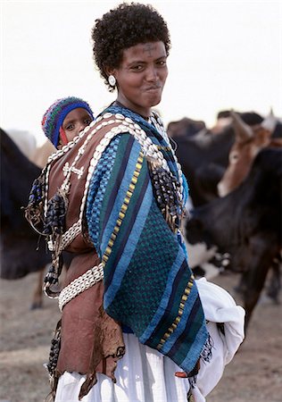 A Tigray woman carries her child in a beautifully decorated leather carrier on her back.She has a cross of the Ethiopian Orthodox Church tattooed on her forehead.The people living in the highlands of Northern Ethiopia are deeply religious. Stock Photo - Rights-Managed, Code: 862-03820377