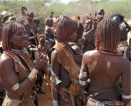 A group of Hamar women at a Jumping of the Bull ceremony.The Hamar are semi nomadic pastoralists of Southwest Ethiopia whose women wear striking traditional dress and style their red ochred hair mop fashion.The Jumping of the Bull ceremony is a rite of passage for young men. Foto de stock - Con derechos protegidos, Código: 862-03820516