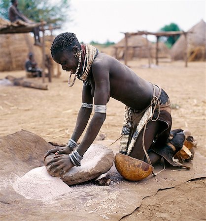 Une femme Nyangatom broie le sorgho à l'aide d'une pierre plate.Le Nyangatom sont une des plus grandes tribus et on peut dire que les gens plus belliqueuses vivant le long de la rivière Omo, au sud-ouest de Ethiopia.They font partie de la Ateger un groupe de sept tribus nilotiques orientales les anglophones dont le Turkana du Kenya du Nord et les Karamajong du nord-est de l'Ouganda font partie. Photographie de stock - Rights-Managed, Code: 862-03820551