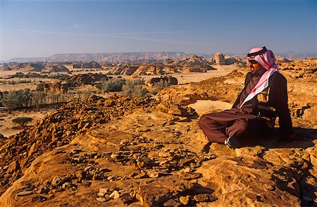 saudi arabia people - Saudi Arabia, Madinah, nr. Al-Ula, Madain Saleh (aka Hegra). A Saudi man gazes at stark cliffs and rocky outcrops that mark the site of Hegra, once an ancient Nabatean settlement and now a UNESCO World Heritage Site. Stock Photo - Rights-Managed, Code: 862-03889525