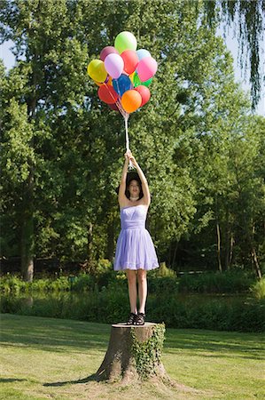 simsearch:877-06834306,k - Young woman holding bunch of balloons, standing on tree stump Stock Photo - Rights-Managed, Code: 877-06834290