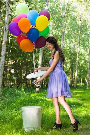 simsearch:877-06834306,k - Young woman throwing away can, bunch of balloons tied to dustbin lid Stock Photo - Rights-Managed, Code: 877-06834301