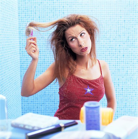 Portrait of woman in bathroom, disentangling her hair, making a face Stock Photo - Rights-Managed, Code: 877-06835898