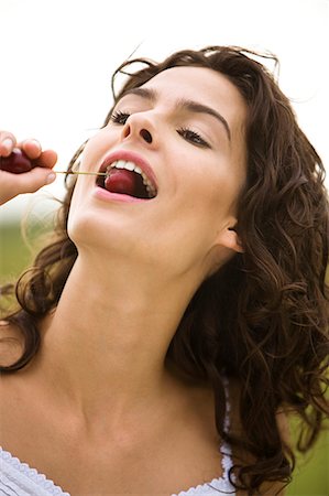 simsearch:877-06832290,k - Young woman eating a cherry, oudoors Stock Photo - Rights-Managed, Code: 877-06832338