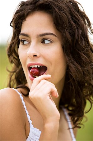 simsearch:877-06832290,k - Young woman eating a cherry, oudoors Stock Photo - Rights-Managed, Code: 877-06832339