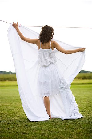 simsearch:877-06832290,k - Young woman hanging a white sheet, oudoors Stock Photo - Rights-Managed, Code: 877-06832342