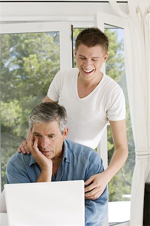 Senior man an young man at home, using laptop Foto de stock - Con derechos protegidos, Código: 877-06832426