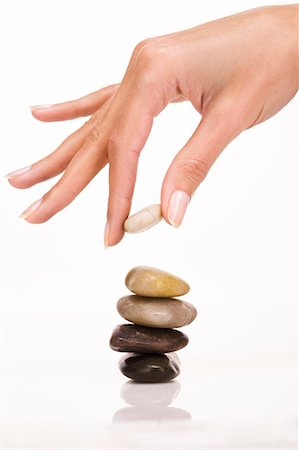 Woman's hand overlaying pebbles Stock Photo - Rights-Managed, Code: 877-06832643
