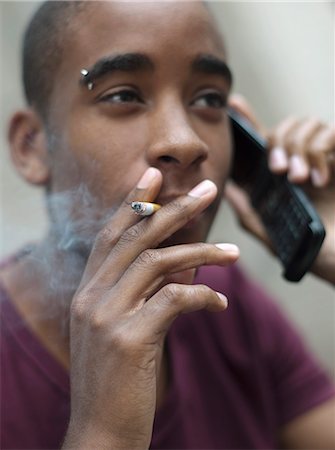 Teenage boy smoking while phoning Stock Photo - Rights-Managed, Code: 877-06833930