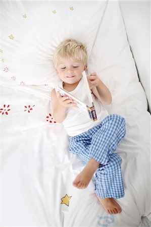 simsearch:640-06963757,k - Little boy lying down on his bed reads a book Stock Photo - Rights-Managed, Code: 877-08128930