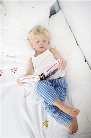 Little boy lying down on his bed reads a book Stock Photo - Rights-Managed, Code: 877-08128931