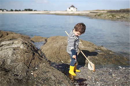 sleeve - 3 years old boy fishing with a net in the rocks near the beach Stock Photo - Rights-Managed, Code: 877-08129106