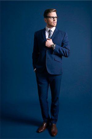 man in blue suit, glasses, blue background; watch; tie Stockbilder - Lizenzpflichtiges, Bildnummer: 877-08129432