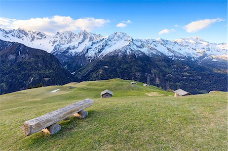 Meadows and wooden huts framed by snowy peaks at dawn Tombal Soglio Bregaglia Valley canton of Graubünden Switzerland Europe Photographie de stock - Rights-Managed, Code: 879-09021239