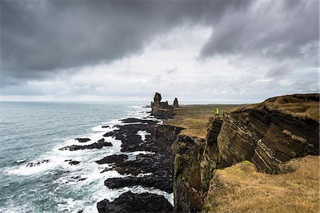 Snaefellsnes Peninsula, Western Iceland, Iceland. Londrangar sea stack and coastal cliffs. A man is standing on the cliff Photographie de stock - Rights-Managed, Code: 879-09032826