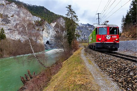 The Red Train passes along the Rhine River. Rhein Gorge(Ruinaulta), Flims, Imboden, Graubunden, Switzerland, Europe Stock Photo - Rights-Managed, Code: 879-09043389