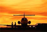 Gens d'affaires à côté de l'avion au coucher du soleil