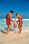 Back View of Family in Swimwear Standing near Water on Beach