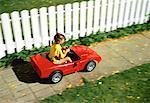 Girl Driving Toy Car on Sidewalk In Autumn