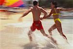 Blurred View of Couple in Swimwear, Running on Beach