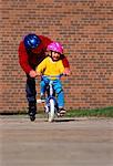 Father In-Line Skating with Daughter Riding Bike