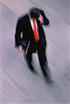 Blurred View of Businessman Walking Outdoors, Using Cell Phone