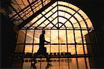 Silhouette of Businessman Walking Near Window at Sunset