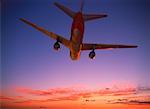 Looking Up at Airplane in Flight At Sunset