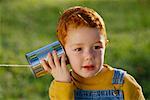 Child Holding Tin Can Telephone Outdoors