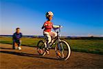 Girl Learning to Ride Bicycle With Mother