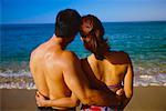 Back View of Couple in Swimwear Embracing on Beach