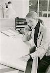 Businesswoman Using Telephone At Drafting Table