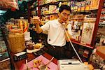 Man Displaying Herbal Medicines In Shop