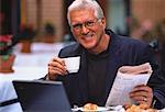 Portrait d'homme d'affaires Mature tenant le journal et la tasse à café en plein air