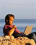 Man Using Laptop Computer on Beach